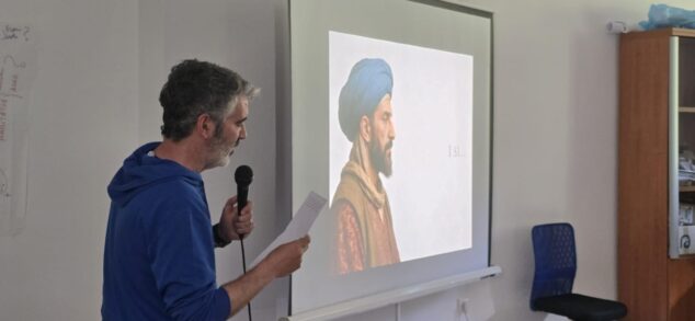 Imagen: Just Sellés dando una conferencia delante de una proyección de Al-Azraq en La Vall de Gallinera.