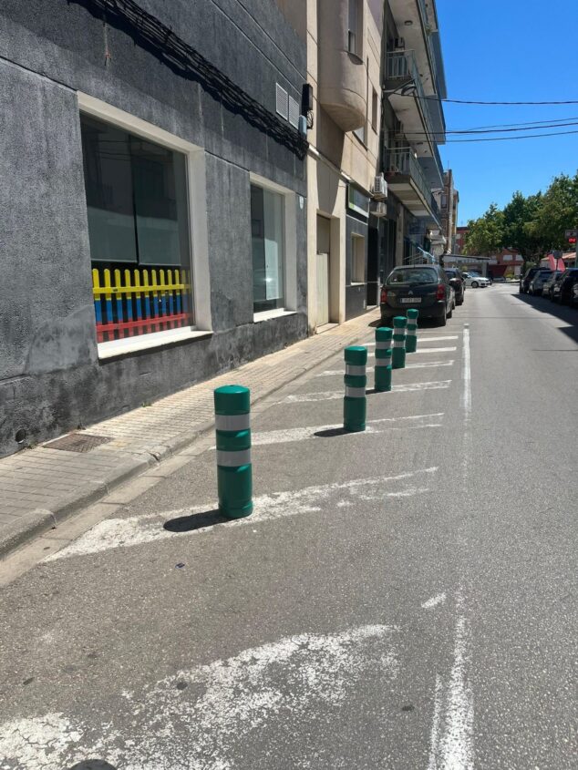 Imagen: Calle en Ondara con nuevas pilonas verdes y blancas a lo largo de la acera para evitar que aparquen coches.