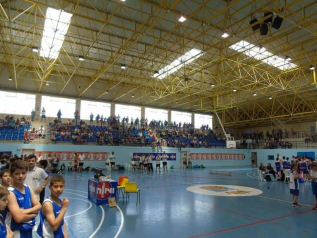Interior del pabellón deportivo Palau Sant Pere de Benissa con público en las gradas y jugadores jóvenes en la pista de baloncesto.