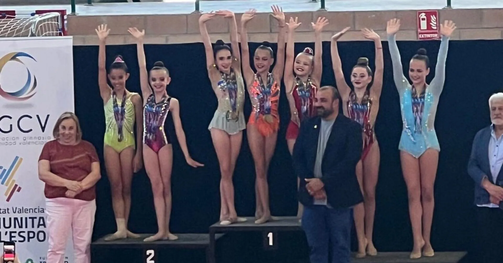 Gimnastas en el podio con medallas y entrenadores durante el Campeonato Provincial de Gimnasia Rítmica en Burjassot.