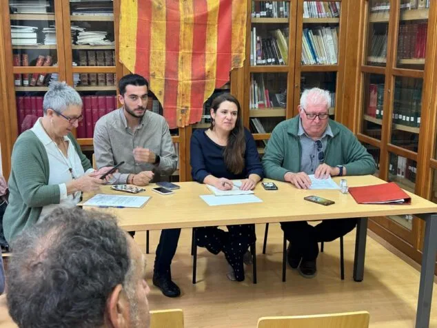 Imagen: Estefania Rovira, Ferran Lloret, Mònica Àlvaro y Rafael Pastor sentados en una mesa con una bandera cuatribarrada de fondo durante una presentación.
