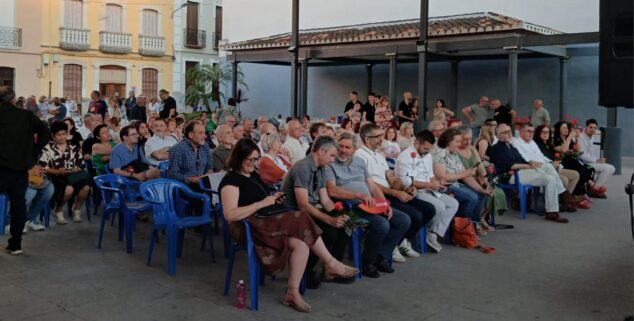 Compromís conmemora 15 años en la alcaldía de Pedreguer y activa su precampaña para 2027 12 Público sentado en sillas azules escuchando un acto político al aire libre en una plaza de Pedreguer.