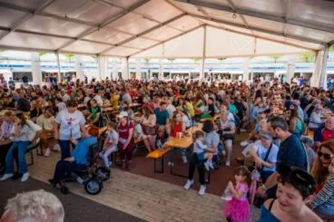 Multitud de personas sentadas en mesas bajo una gran carpa durante la feria FiraCalp.