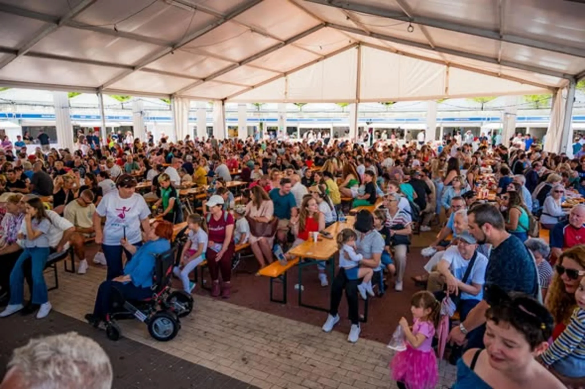 Multitud de personas sentadas en mesas bajo una gran carpa durante la feria FiraCalp.
