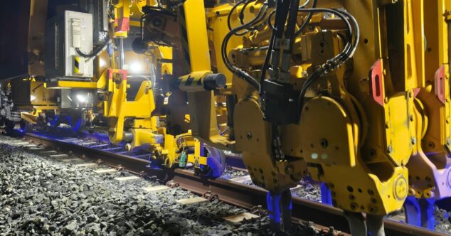 La técnica que mejora los viajes en el TRAM d'Alacant de Dénia a Benidorm 9 Primer plano de maquinaria ferroviaria amarilla realizando trabajos de bateo en las vías del TRAM d'Alacant durante la noche.