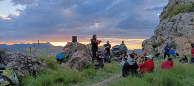 Imagen: Asistentes escuchan una actuación musical al aire libre al atardecer en las montañas de La Vall de Gallinera.