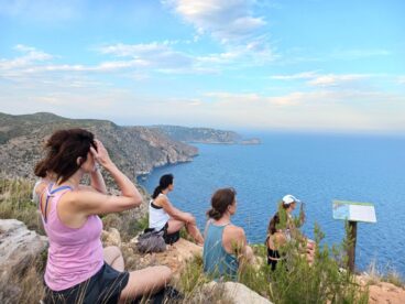 «Respira l’estiu», las meditaciones guiadas de Benitatxell, vuelven para un verano de bienestar consciente 3 Grupo de personas sentadas en un acantilado mirando al mar durante una sesión del ciclo 'Respira l'estiu' en Benitatxell.