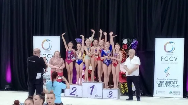 Gimnastas del Club Calpe en el podio con trofeos, celebrando su clasificación para el campeonato nacional.