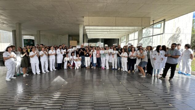Imagen: Grupo numeroso de trabajadores sanitarios con batas blancas y uniformes protestando con pancartas en la entrada techada del Hospital de Dénia.