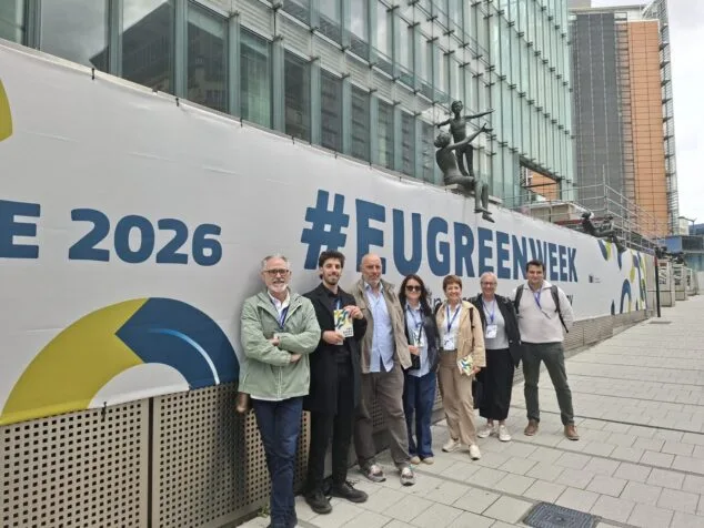 Siete personas de la delegación de Pedreguer posan frente a un gran cartel blanco con el texto '#EUGREENWEEK' y 'E 2026' en Bruselas.