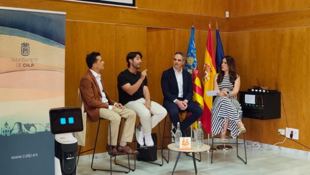Calp reúne a expertos y empresas para abordar los retos del envejecimiento y la innovación 4 Imagen: Mesa redonda en el evento Focus Pyme Calp con cuatro ponentes y un robot en el escenario, con banderas institucionales y un cartel del Ayuntamiento de Calp de fondo.