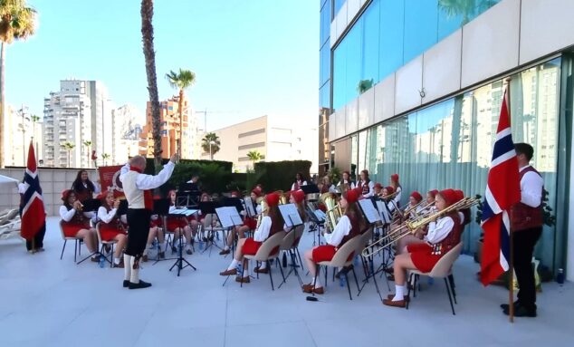 Imagen: La banda femenina noruega Haslum Skoles Jentekorps, con trajes tradicionales y banderas de Noruega, toca instrumentos de viento al aire libre en Calp.