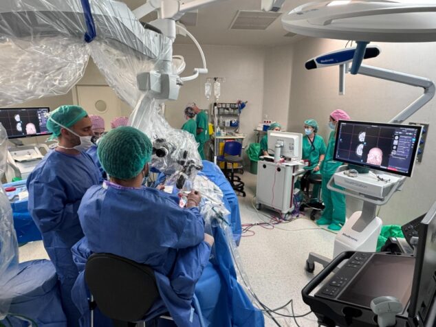 Imagen: Equipo médico en quirófano realizando una neurocirugía con microscopio y monitores de visualización.