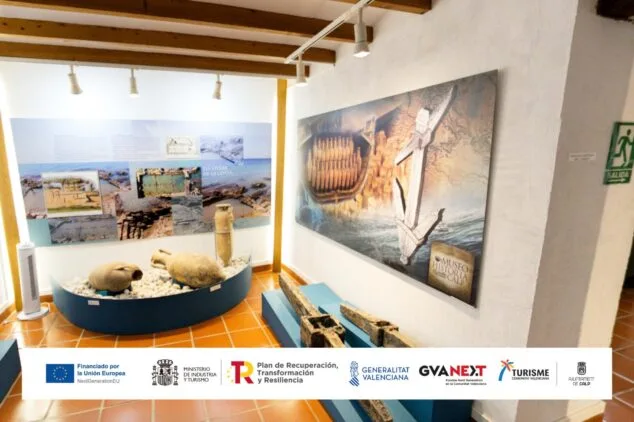 Calp lanza visitas virtuales inmersivas al Penyal d’Ifac, Banys de la Reina y su casco antiguo 3 Imagen: Interior del Museo de Historia de Calp con exhibición de ánforas, paneles informativos y un gran cartel con un ancla. En la parte inferior, logotipos de las entidades financiadoras del proyecto.