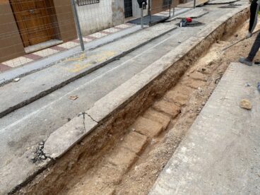El Ayuntamiento de Gata acusa al PP de «manipulación» y «bloqueo» en las obras de la Bassa y Duquessa d'Almodóvar 2 Rasa profunda en una calle en obras con restos de piedra antigua visibles y un operario trabajando.
