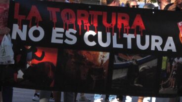 Pancarta sostenida por personas con el texto "LA TORTURA NO ES CULTURA" y cuatro imágenes gráficas relacionadas con la tauromaquia.