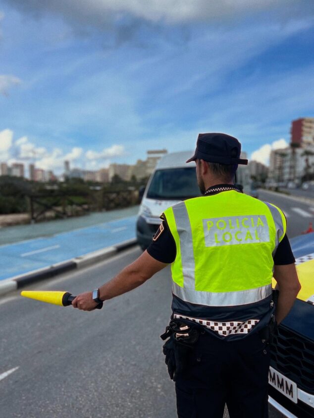 Imagen: Un agente de la Policía Local de Calp con chaleco reflectante amarillo y una linterna de tráfico.