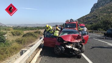 Trágico accidente con un fallecido y dos heridos en un choque frontal en la N-332 entre El Verger y Ondara 2 Bomberos trabajando sobre un coche rojo siniestrado tras un accidente de tráfico en la carretera N-332.