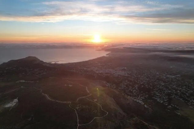 Alerte maximale dans la Communauté valencienne : la Generalitat interdit l'accès aux parcs naturels et aux zones forestières en raison du risque extrême d'incendies. Image : Photographie d'un lever de soleil avec le soleil se levant sur la mer et le massif montagneux du parc naturel du Montgó au premier plan.