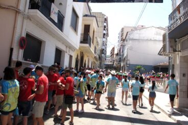 Calle concurrida con gente festejando durante el día en Pedreguer.