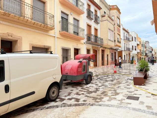 Furgoneta blanca y máquina de limpieza roja de Poble Net en una calle adoquinada de Benitatxell.