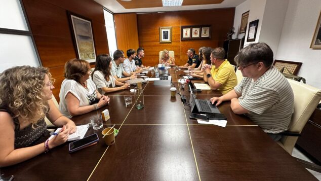 Imagen: Reunión de coordinación en una sala del Ayuntamiento de Calp con varios asistentes y policías alrededor de una mesa larga, planificando el dispositivo de seguridad para la final del Mundial.