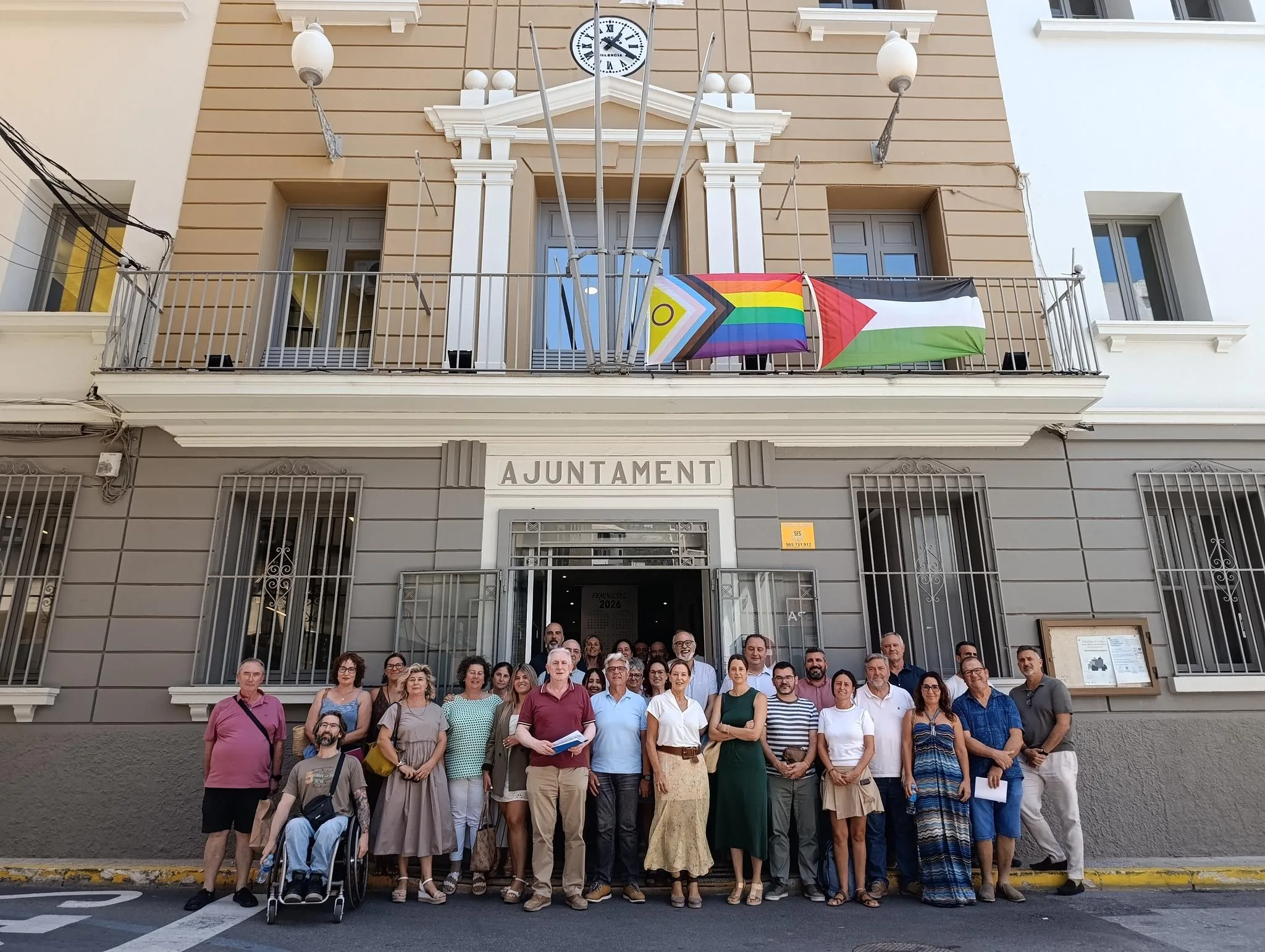 Grupo de personas posando frente a la fachada del Ayuntamiento de Pedreguer tras una reunión.