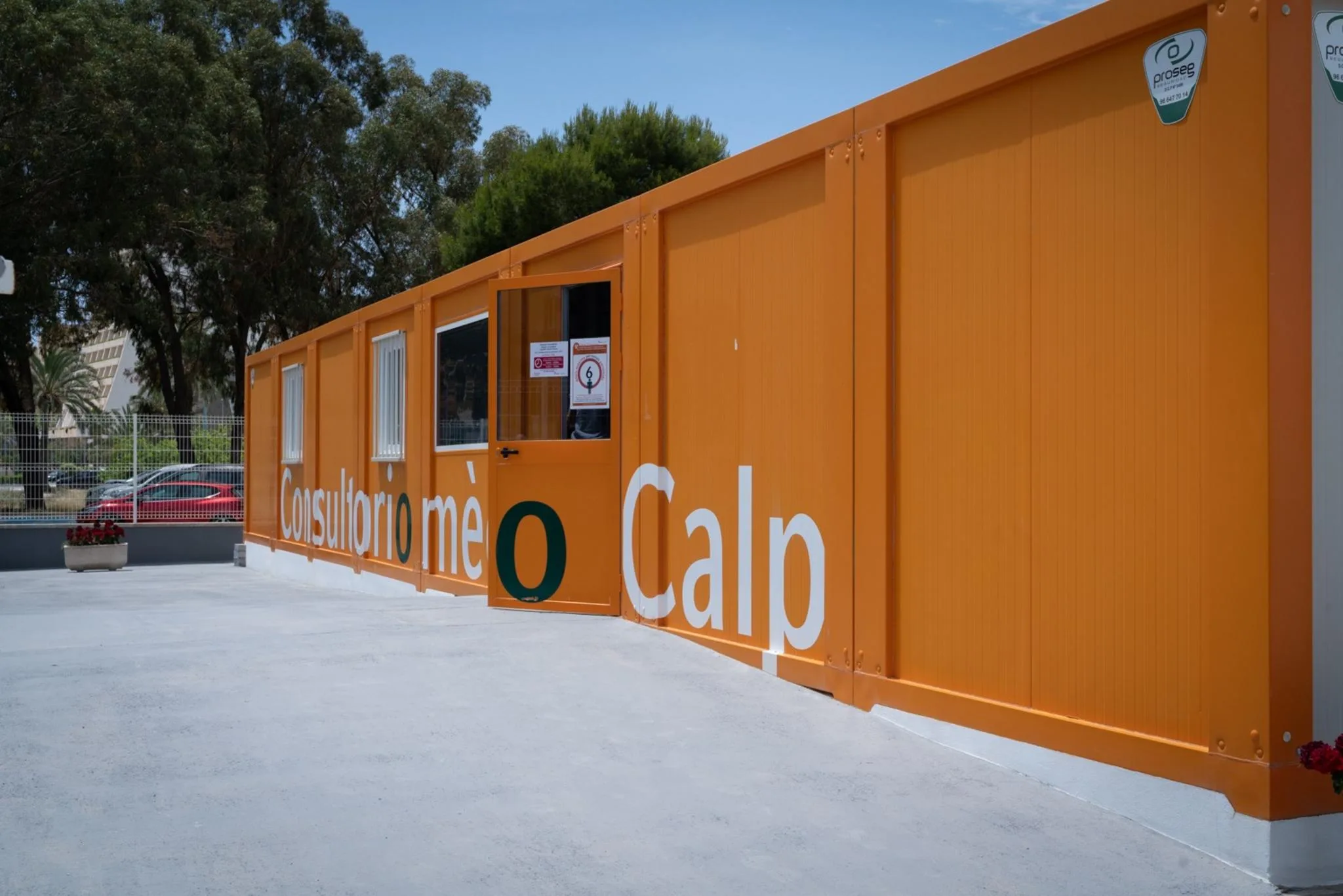Fotografía del exterior del consultorio médico modular de color naranja con el texto "Consultorio médico Calp".