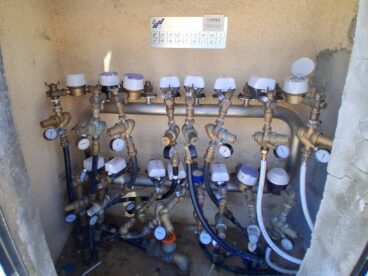 Varios contadores de agua digitales con tecnología de telelectura instalados en un armario de servicio.