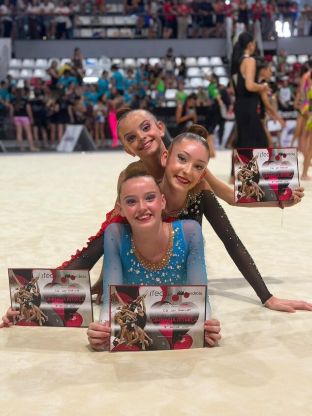 Sophie O'Reilly, del Club Les Marines de Calp, Campeona de España de gimnasia rítmica en pelota 13 Tres gimnastas del Club Les Marines sostienen diplomas en un tapiz de competición.