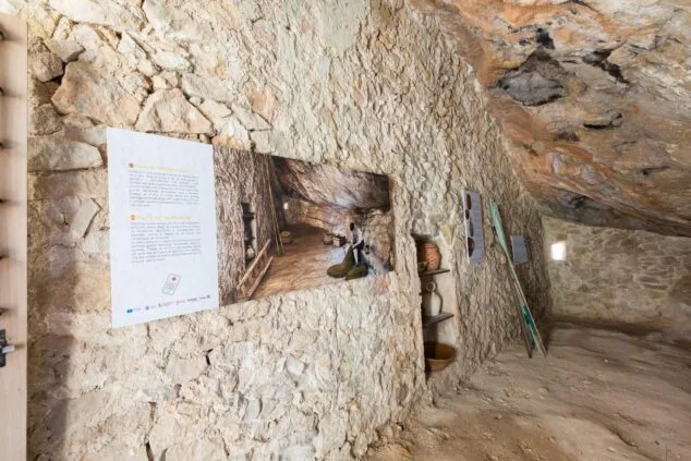 Imagen: Interior de la cueva Cova de les Morretes convertida en museo con paneles explicativos y objetos antiguos.