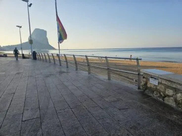 Personas paseando por el paseo marítimo Arenal-Bol en Calp con el Peñón de Ifach al fondo.