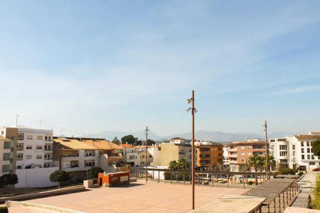 Imagen: Vista de la Plaza de VI Centenari en Teulada, con suelo pavimentado y pocos árboles bajo un cielo soleado.