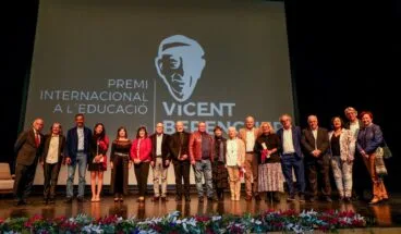 Grupo de dieciséis personas posando en un escenario con una pantalla de fondo que dice 'Premi Internacional a l'Educació Vicent Berenguer'.