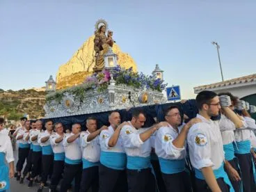 Procession of the Virgen del Carmen in Calp with bearers carrying the throne and the Peñón de Ifach behind.