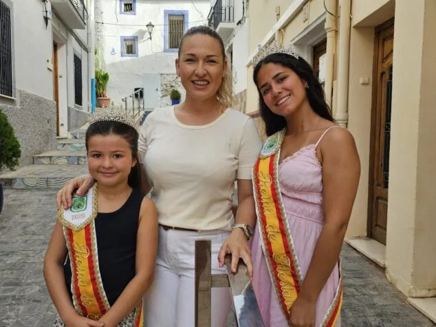 Imagen: Reinas de las fiestas de Calp 2026, Sofía Fonte y Maria Rubio, con una representante del Ayuntamiento en una calle del casco antiguo.