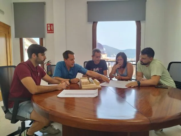 Imagen: Varios asistentes en una mesa redonda revisan planos y una maqueta de madera del futuro trinquet.