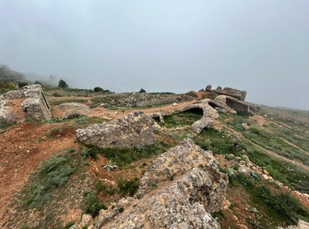Imagen: Vista de las ruinas de piedra y restos de muralla del Castillo de Bernia entre la niebla.