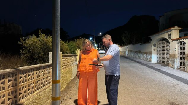 Más luz en Calp: 67 nuevas farolas solares iluminan sus urbanizaciones 2 Imagen: La alcaldesa Ana Sala y el concejal Pere Moll revisan una tablet de noche bajo una nueva farola solar en una calle de Calp.