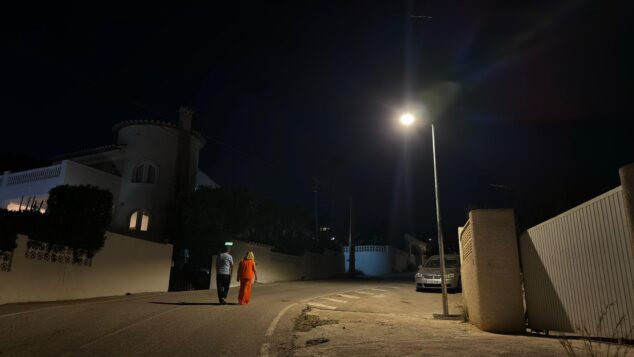 Más luz en Calp: 67 nuevas farolas solares iluminan sus urbanizaciones 1 Imagen: Ana Sala y Pere Moll caminando de noche bajo una nueva farola solar encendida en una calle de Calp.