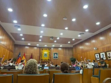 Miembros del Pleno del Ayuntamiento de Calp con la mano levantada votando unánimemente el reglamento de carrera profesional en el salón de sesiones.