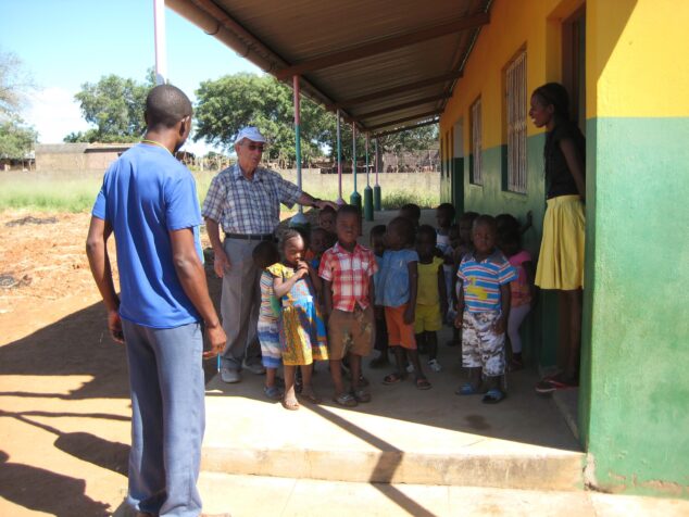 Imagen: Berenguer, con su característica gorra, junto a un grupo de niños y niñas locales a las puertas del centro educativo