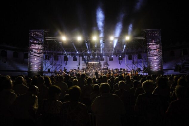 Imagen: Vista general nocturna de un concierto de orquesta con gran afluencia de público en un recinto al aire libre.