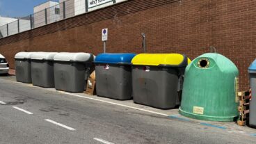 Fila de contenedores de basura y reciclaje de distintos colores en una calle de Calp.