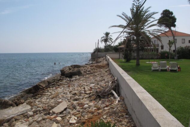 Vista de la costa de Dénia con un muro de separación y viviendas con jardín cercanas al mar.