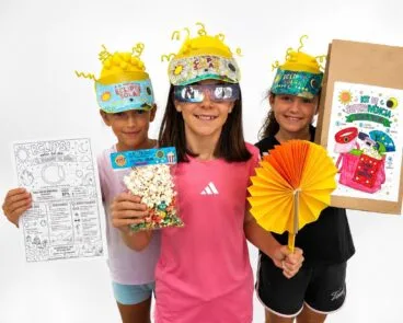 Tres niñas de la Escuela de Verano de Benitatxell posan con viseras, gafas y materiales del kit para el eclipse solar.