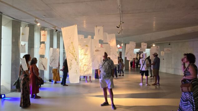 «Arrels Mediterrànies» abre Alere/Dolia 2026 con el arte de Ximo Canet como puente entre el mar y la tierra 2 Imagen: Vista de la sala de exposiciones con personas observando las obras colgantes de la muestra "Arrels Mediterrànies" de Ximo Canet.