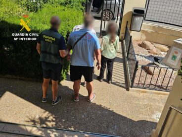 Agente de la Guardia Civil escoltando a dos personas detenidas en la operación en Calpe.
