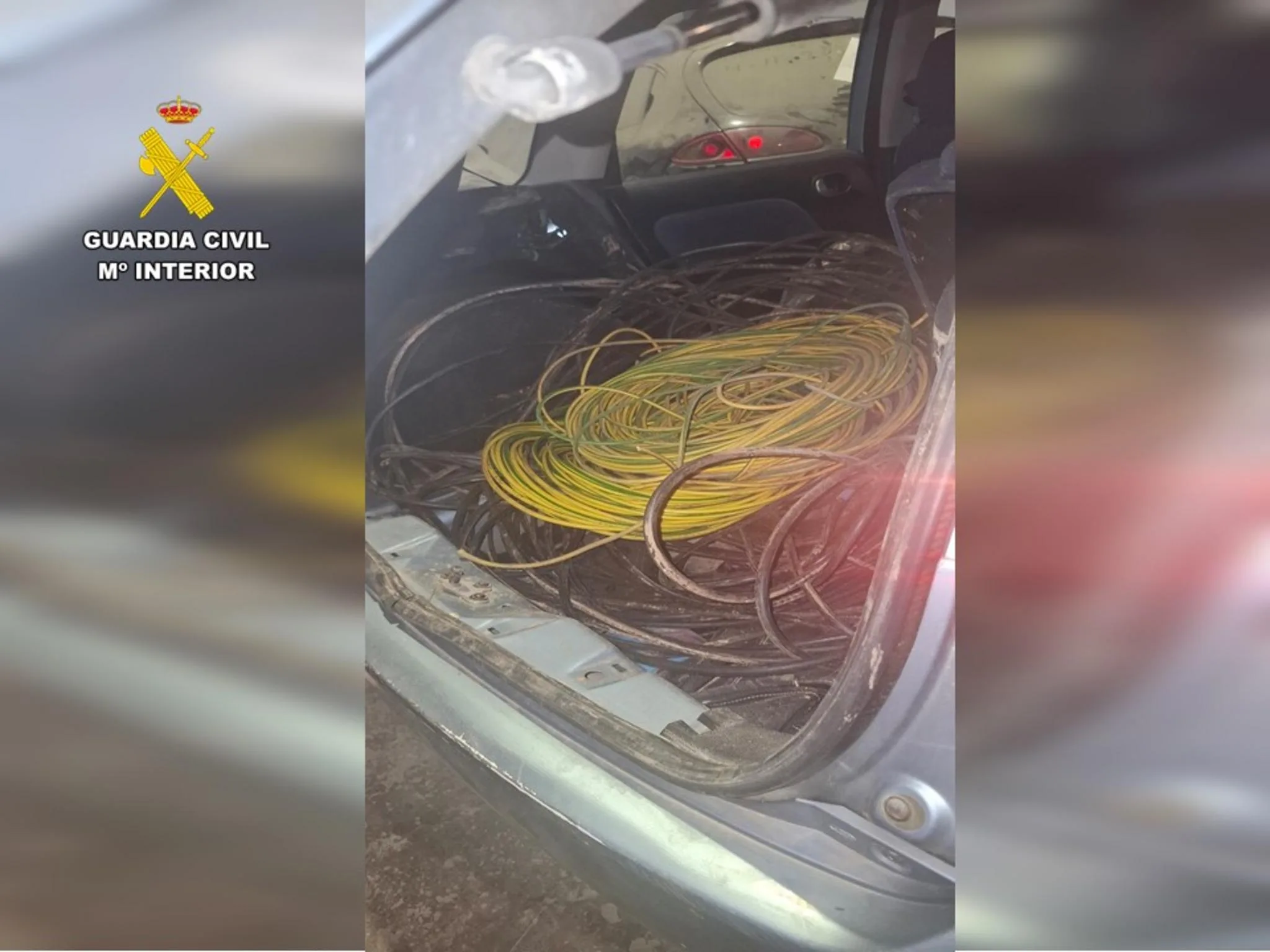 Maletero de un coche lleno de rollos de cable eléctrico de cobre recuperado, con el logotipo de la Guardia Civil en la esquina superior izquierda.