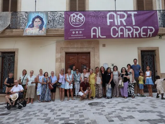 Imagen: Foto de grupo de personas posando bajo una pancarta que dice 'Art al carrer' y 'Dones Picanya' frente a un edificio.